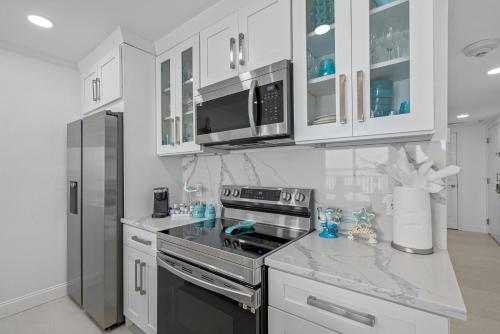 a kitchen with white cabinets and a stove top oven at Welcome to Sea Forever Balcony with ocean views! in Tampa