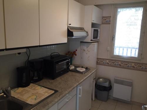 une cuisine avec un micro-ondes et un plan de travail dans l'établissement Grand studio familial avec balcon et parking à 2 pas de la plage et du centre de Villers-sur-Mer - FR-1-712-2, à Villers-sur-Mer