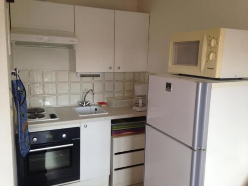 une cuisine avec des armoires blanches et un réfrigérateur blanc dans l'établissement Appartement 2 Pièces avec Balcon Sud à 50m de la Plage, Parking Privatif - Villers-sur-Mer - FR-1-712-15, à Villers-sur-Mer
