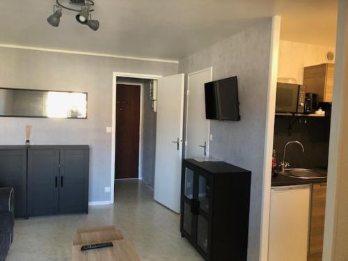 un salon avec une armoire noire et une cuisine dans l'établissement Appartement charmant proche plage et commerces - FR-1-712-13, à Villers-sur-Mer