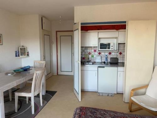 une cuisine avec des armoires blanches et une table et des chaises dans l'établissement Appartement 2 pièces centre de Villers-sur-Mer avec parking - FR-1-712-40, à Villers-sur-Mer