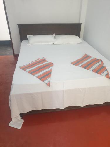 a bed with a white bedspread and two pillows at Nature guesthous in Midigama
