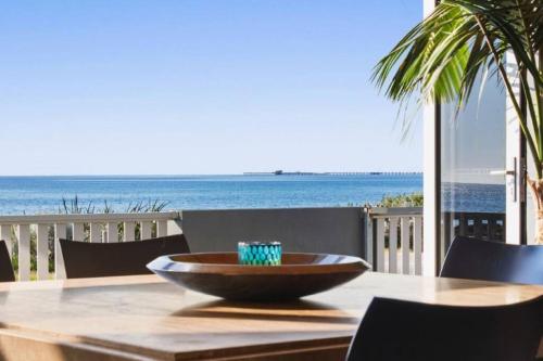 a wooden bowl on a table with a view of the ocean at THE DECK HOUSE - Beautiful Busselton Beachfront in Busselton