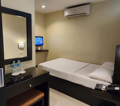 a small room with a bed and a mirror at Green Glass Hotel in Calamba