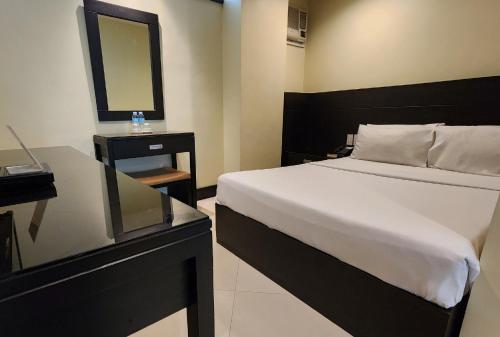 a bedroom with a large bed and a mirror at Green Glass Hotel in Calamba