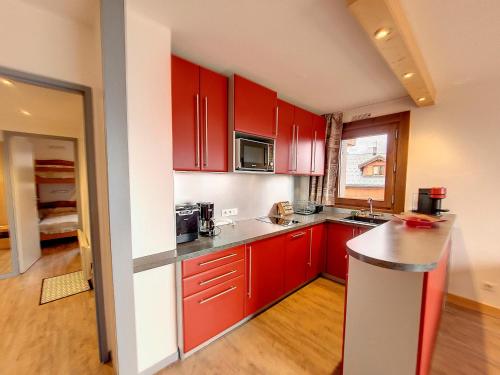 une cuisine avec des armoires rouges et un comptoir dans l'établissement Appartement lumineux avec balcon - 2 chambres - 5 personnes - Centre station - FR-1-275-198, à La Rosière