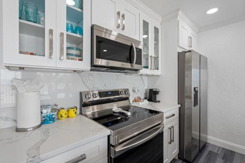 a kitchen with white cabinets and a stainless steel refrigerator at Bay Views from your Balcony Beach Resort Tampa in Tampa