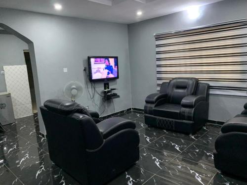 sala de estar con 2 sillas y TV de pantalla plana en New Bungalow 2 Bed House in Adewumi, Off Olodo rd Ibadan, en Ibadán