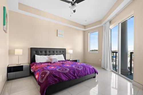 a bedroom with a purple bed and large windows at Bali Bay 403 OV Myrtle Beach Hotel Room in Myrtle Beach