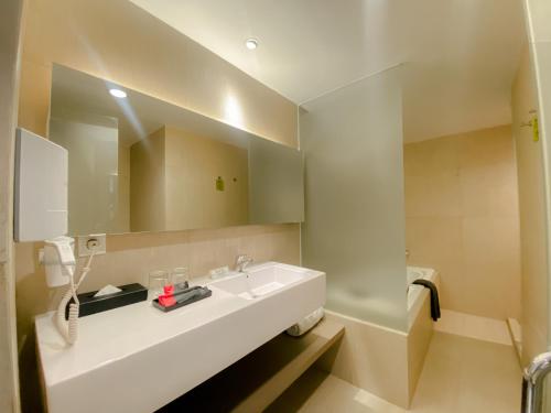 La salle de bains est pourvue d'un lavabo blanc et d'un miroir. dans l'établissement Grand Zuri Dumai, à Dumai
