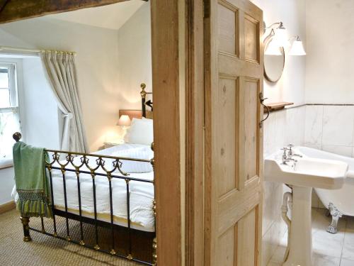 a bathroom with a bed and a sink and a mirror at Norfolk House in Dulverton