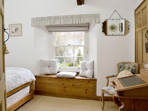 a bedroom with a window with a bed and a chair at Norfolk House in Dulverton