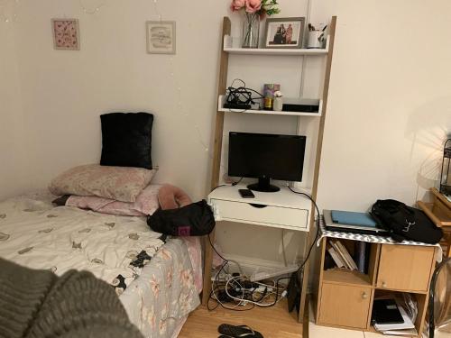 Studio flat in Stratford في لندن: غرفة نوم مع سرير ومكتب مع جهاز كمبيوتر