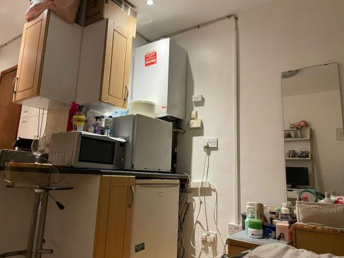 a cluttered kitchen with a microwave and a refrigerator at Studio flat in Stratford in London