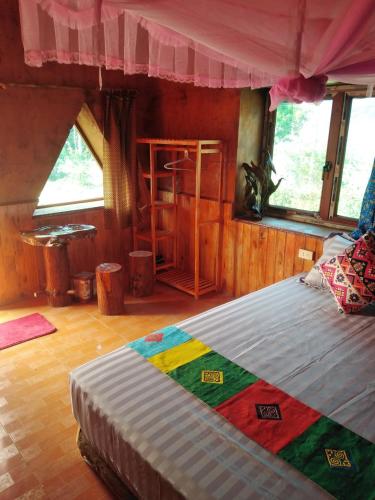 a bedroom with a large bed in a room with windows at Diềm Bungalow in Ha Giang
