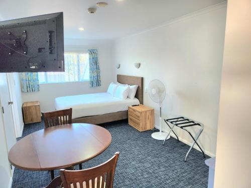a small hotel room with a bed and a table and a table at Botany Palms Motel in Auckland