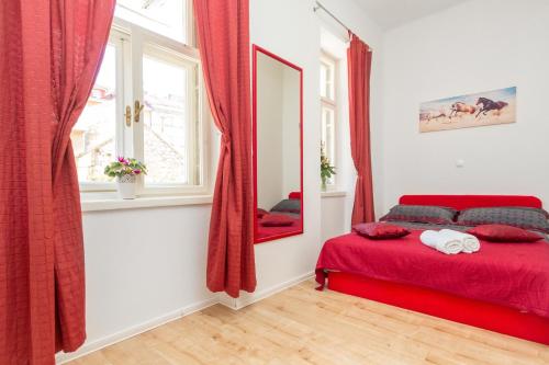 a bedroom with a red bed and a mirror at Central Jardin Guest House Split in Split