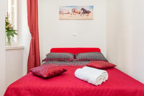 Cama roja con almohadas rojas y manta roja en Central Jardin Guest House Split en Split