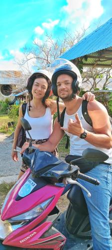 a man and woman wearing helmets on a scooter at House of TamSe Laagans ' Inn in Badian