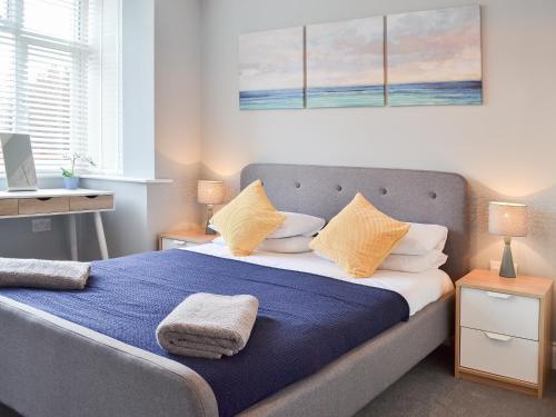 Schlafzimmer mit einem Bett mit blauer Bettwäsche und gelben Kissen in der Unterkunft Carr Lodge in York