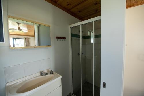 a bathroom with a sink and a glass shower at Sarina Palms Caravan and Cabins Village in Sarina