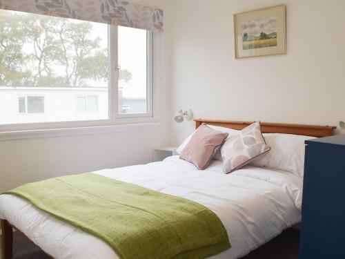 a white bed with a green blanket and a window at Sanderling - Uk32837 in Hodgeston
