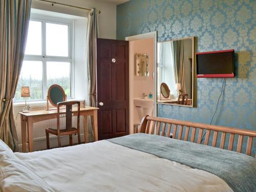 a bedroom with a bed and a desk and a window at Dunley Farmhouse in Bovey Tracey