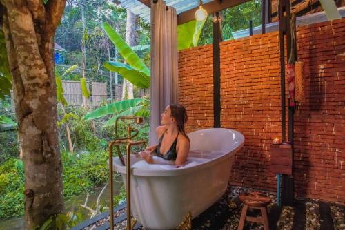 a woman sitting in a bath tub in a garden at Voraman B-One in Chiang Mai