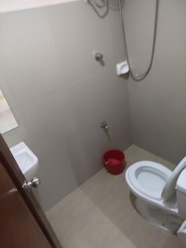 a bathroom with a white toilet and a red bucket at La Casa Milagrosa in Coron
