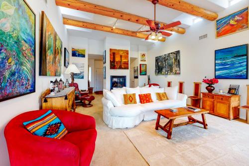 Casa Vistoso في سانتا فيه: غرفة معيشة مع أريكة بيضاء وكرسي احمر
