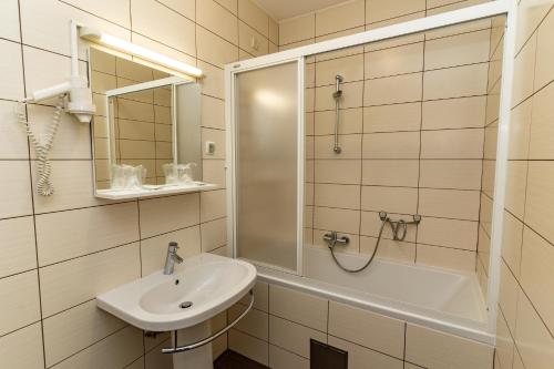 a white bathroom with a sink and a shower at Artearia Hotel in Bjelovar