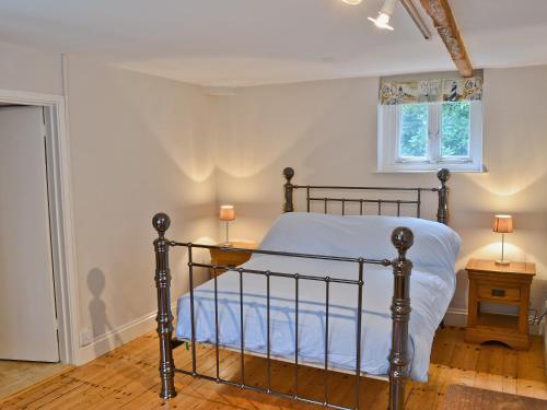 a bedroom with a bed with blue sheets and a window at The Old Stables in Cley next the Sea