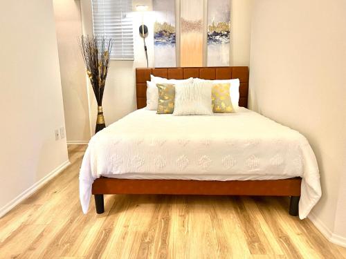 a bedroom with a bed with white sheets and wooden floors at Le Jardin - Remote Work Getaway in SoCal in Irvine