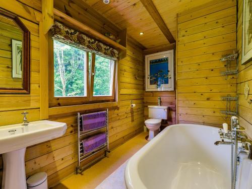 a bathroom with a tub and a sink and a toilet at Ash Mill Cabin in Ashreigney