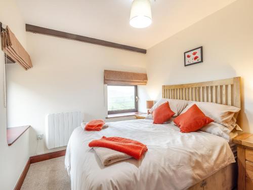 1 dormitorio con 1 cama con almohadas de color naranja en Poppies Court Jericho Farm en Earl Sterndale
