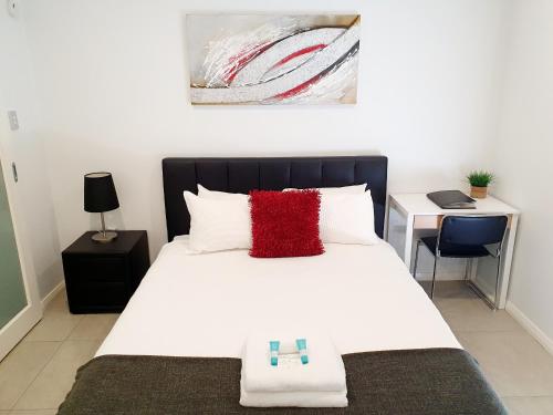 1 dormitorio con cama blanca grande y almohada roja en M5 West Perth Studio Apartment near Kings Park en Perth
