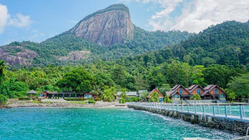 a river with houses and a mountain in the background at Tunamaya Beach & Spa Resort Tioman Island in Tioman Island