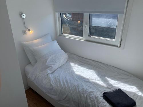 a white bed in a room with a window at Tiny Houseboat B&B on the Amstel River in Amsterdam