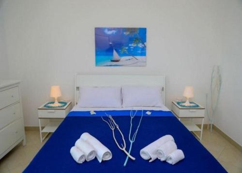 1 dormitorio con 1 cama azul y 2 toallas blancas en STELLE GEMELLE a 350 mt dalla spiaggia e 50 dal centro, con Wi-fi e completamente accessoriate, en Torre Lapillo