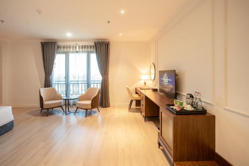a hotel room with a desk and a tv and a room at Rex Quang Binh Hotel in Dong Hoi