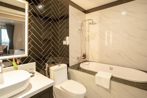 a bathroom with a toilet and a sink and a tub at Rex Quang Binh Hotel in Dong Hoi