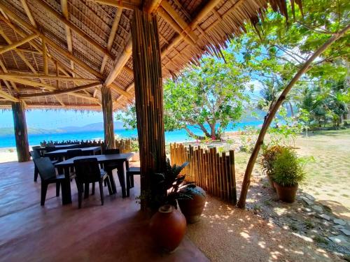 um restaurante com mesa e cadeiras na praia em Sea u inn em Romblon