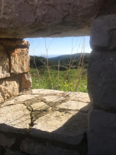 a window in a stone wall with a view of a field at KYTHIRA ISLAND RETREAT in Áyios Ilías