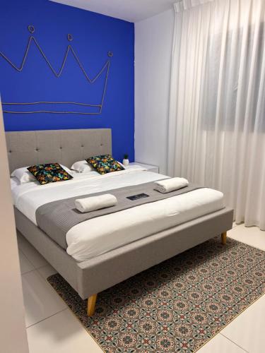 a bedroom with a king sized bed with a blue wall at דירת גן דלוקס-Deluxe Garden Apartment by CRWON in Eilat