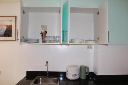 a kitchen with white cabinets and a sink at Premiere Haven MOA Staycation in Manila