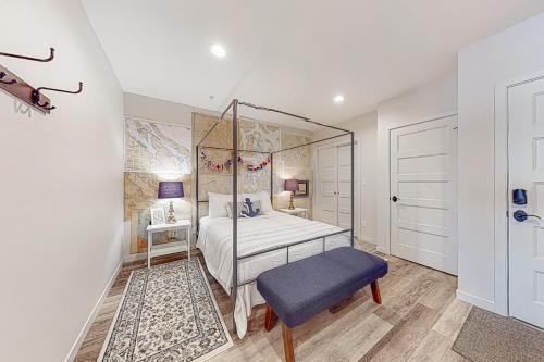 1 dormitorio con cama con dosel y taburete azul en Penn Cove Strand #E en Coupeville
