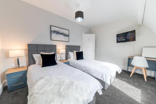 a bedroom with two beds and a desk with a chair at Stylish Luxury Large 4BR KingBed in Barrow in Furness