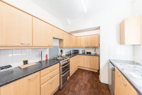 a large kitchen with wooden cabinets and appliances at Stylish Luxury Large 4BR KingBed in Barrow in Furness