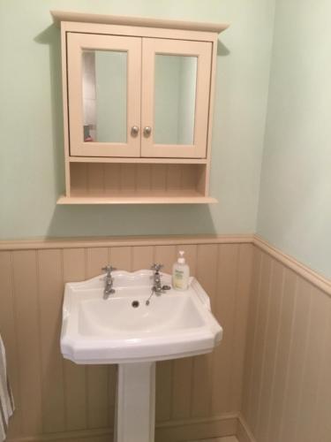 La salle de bains est pourvue d'un lavabo et d'une armoire à médicaments. dans l'établissement Cute Cottage 2024 Traveller Award, à Yateley