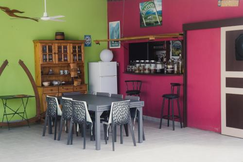 comedor con mesa, sillas y pared rosa en Le Quindio, en Bras-Panon